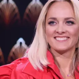 Uśmiechnięta Aleksandra Radwan w czerwonej marynarce, gotowa do zgadywania w "Jaka to melodia?".