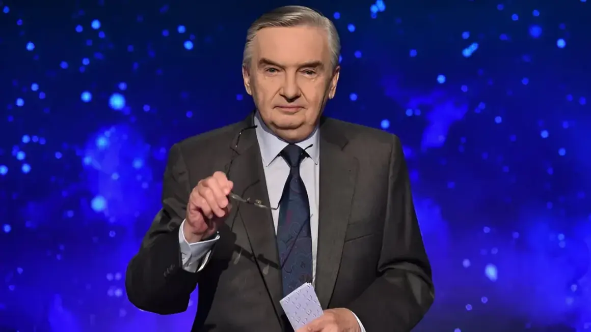 Starsza, siwowłosa osoba w garniturze, która prowadzi jeden z dziesięciu, trzyma okulary i kartkę.